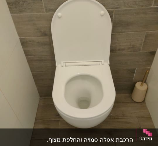 אסלה לבנה עם מברשת שירותים על רצפת עץ